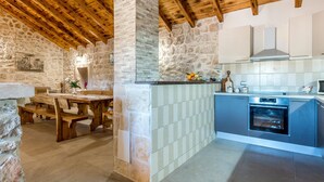 A rustic kitchen with stone walls, wooden beams, and a built-in oven.