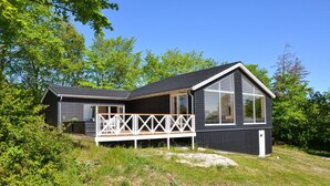 Eine zweistöckige Holzhütte mit Balkon, umgeben von Grün.