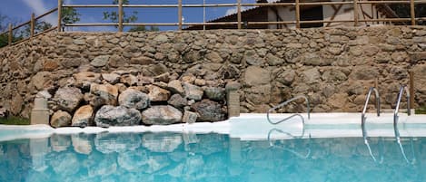 Una piscina al aire libre de temporada, sillones reclinables de piscina