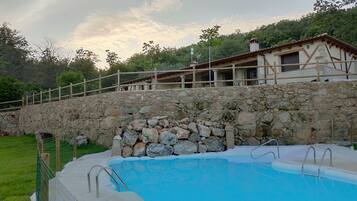 Un muro de piedra con una piscina y una valla de madera.