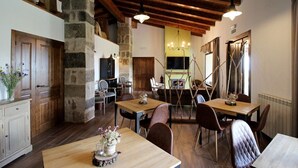 A rustic dining area with wooden tables and chairs, stone walls, and exposed wooden beams. - Hotel Rural San Giles (Aldeanueva de la Vera)