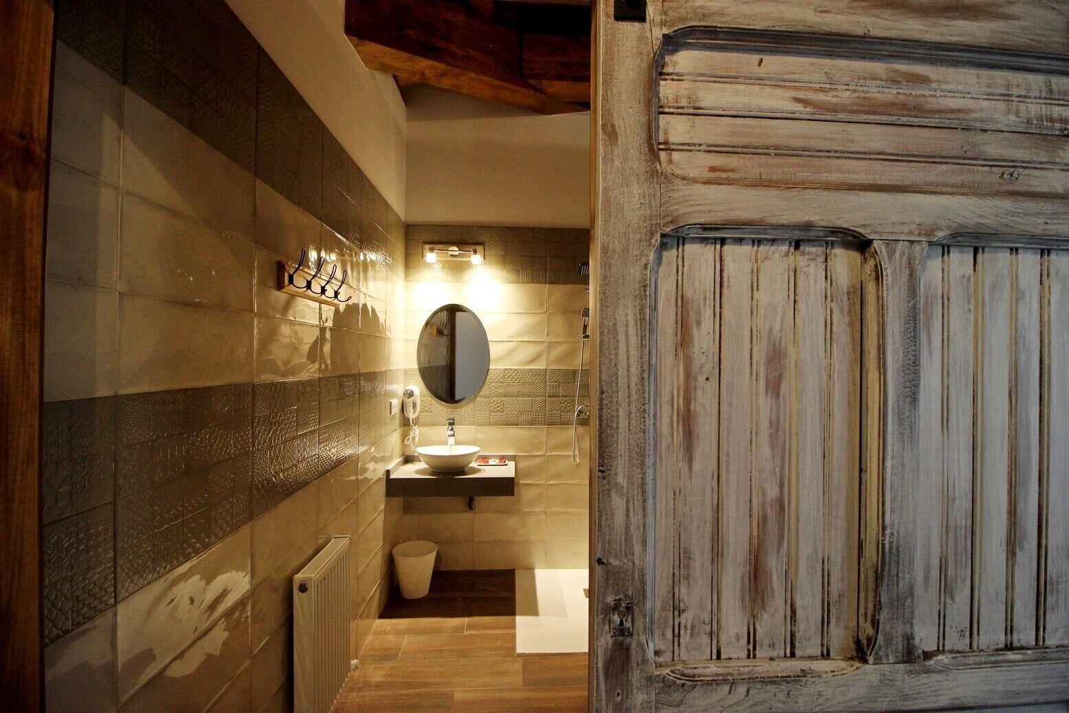 Een badkamer met een houten deur, een spiegel, een wastafel en een toilet.