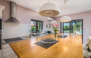 Enjoy cooking in this well-equipped kitchen with a central island, stainless steel range hood, oven, and sink, offering a view of the outdoors.