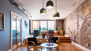 A modern interior with a brick wall, wooden flooring, and a dining area with chairs and a table. - Quaint Historic Downtown: Walk to Dinner & Shops, Poker Table, Rooftop, Garage (New Albany)