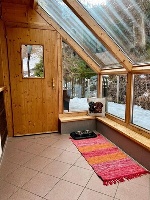 Cozy cabin room with a sloped ceiling, wooden door, and a bench with cushion.