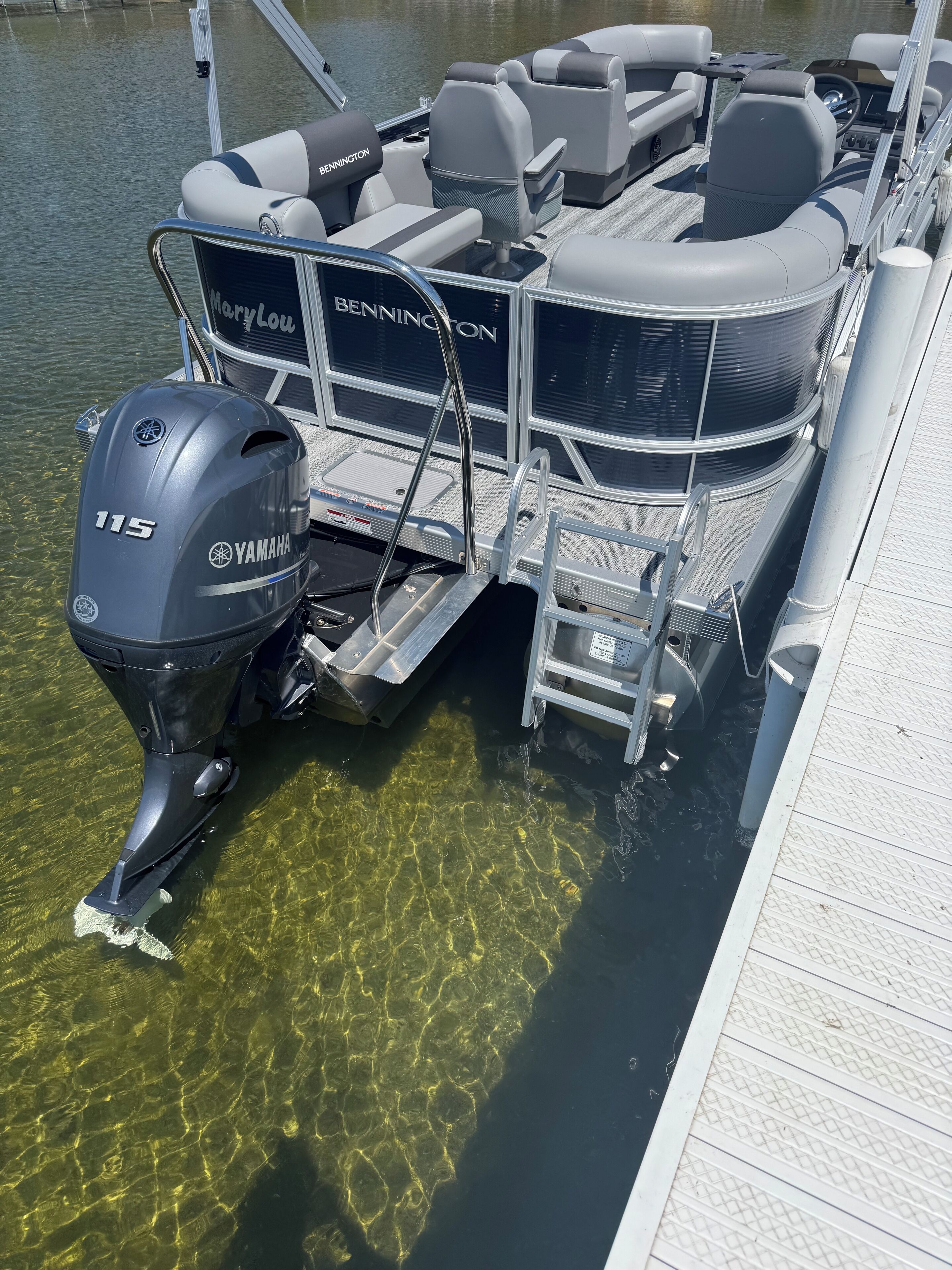 A boat with a Yamaha 115 outboard motor, clear water, and a dock.