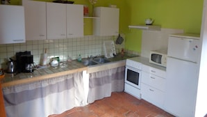 Una cocina con armarios blancos, salpicadero azulejado, un fregadero, una estufa y un refrigerador.