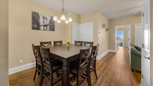 A dining room with a large wooden table and chairs, a chandelier, and a painting on the wall. - motley crew , when you need the space for your big group of personalities  (Myrtle Beach)