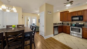 A modern kitchen with wooden cabinets, stainless steel appliances, and a dining area with a wooden table and chairs. - motley crew , when you need the space for your big group of personalities  (Myrtle Beach)