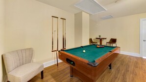 A pool table with a green felt surface, a beige armchair, and wooden flooring. - motley crew , when you need the space for your big group of personalities  (Myrtle Beach)