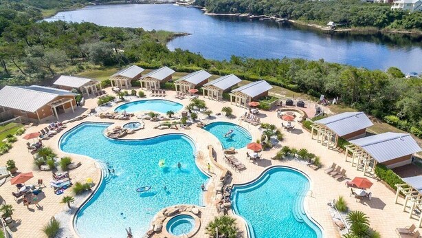 Un complexe hôtelier doté de plusieurs piscines, d’espaces de détente et offrant une vue sur un lac.