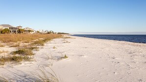 Ein Strand mit klarem Himmel, sandigem Ufer und Strandhäusern.