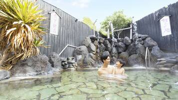 A hot spring area with a wooden fence, a waterfall feature, and a clear pool.