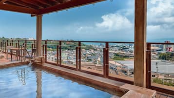 A wooden deck with a pool, a view of a cityscape, and a clear sky.