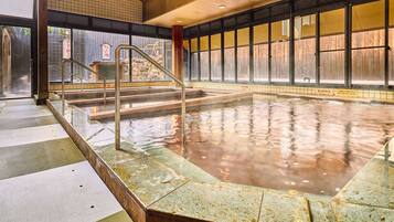 Relax in a serene hot spring bath surrounded by natural light and tranquil surroundings.
