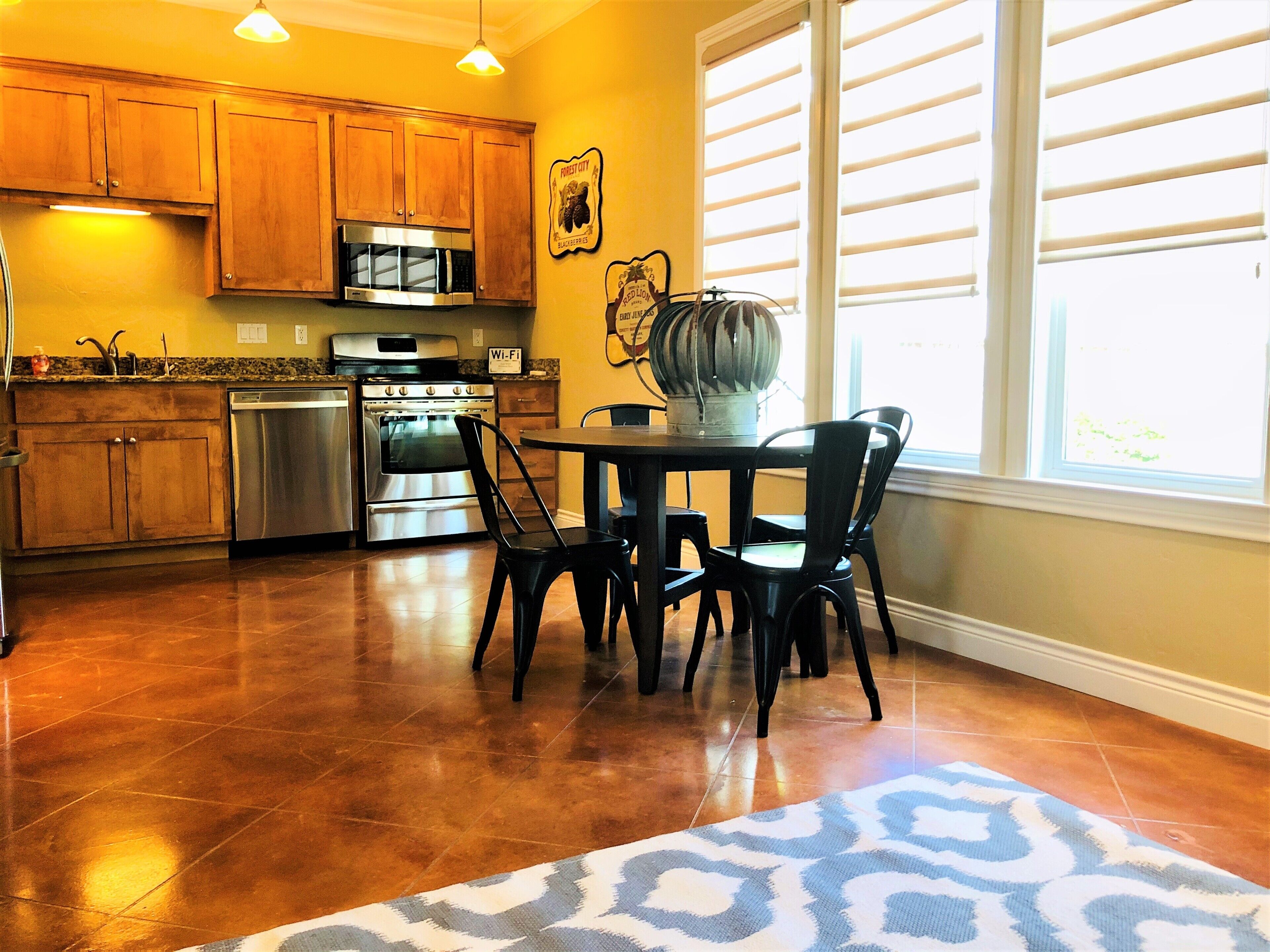 A kitchen with wooden cabinets, stainless steel appliances, and a dining area with a table and chairs.