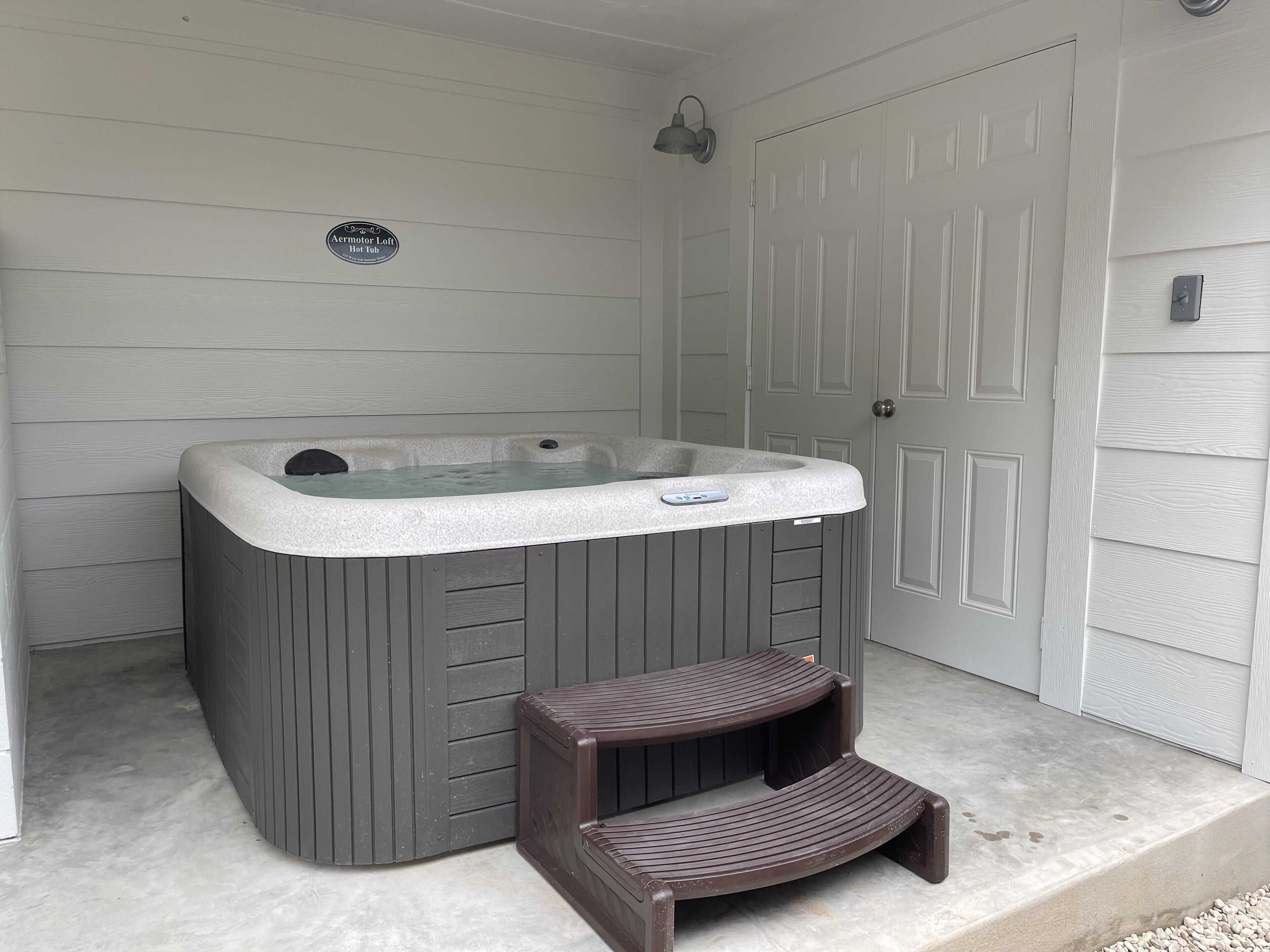 A spa area with a hot tub, a wooden bench, and a door.