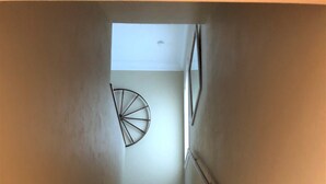 Un escalier en bois avec une rampe, menant à un palier doté d’un ventilateur de plafond.