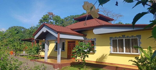 A two-story house with a red roof, yellow walls, and a small porch.