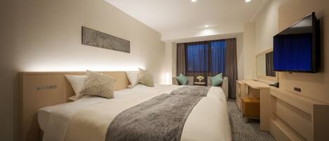 Habitación de hotel con una cama grande, un escritorio, un televisor y una ventana con cortinas.