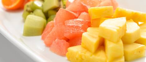 Un plato blanco con varias frutas, incluyendo sandía, piña y kiwi.