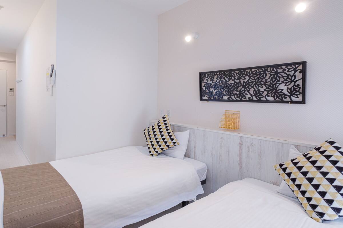 A hotel room with two beds, a desk with a mirror, and a decorative wall piece.