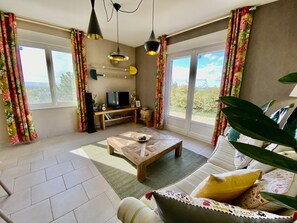 Una sala de estar con sofá, mesa de centro, televisor y cortinas.