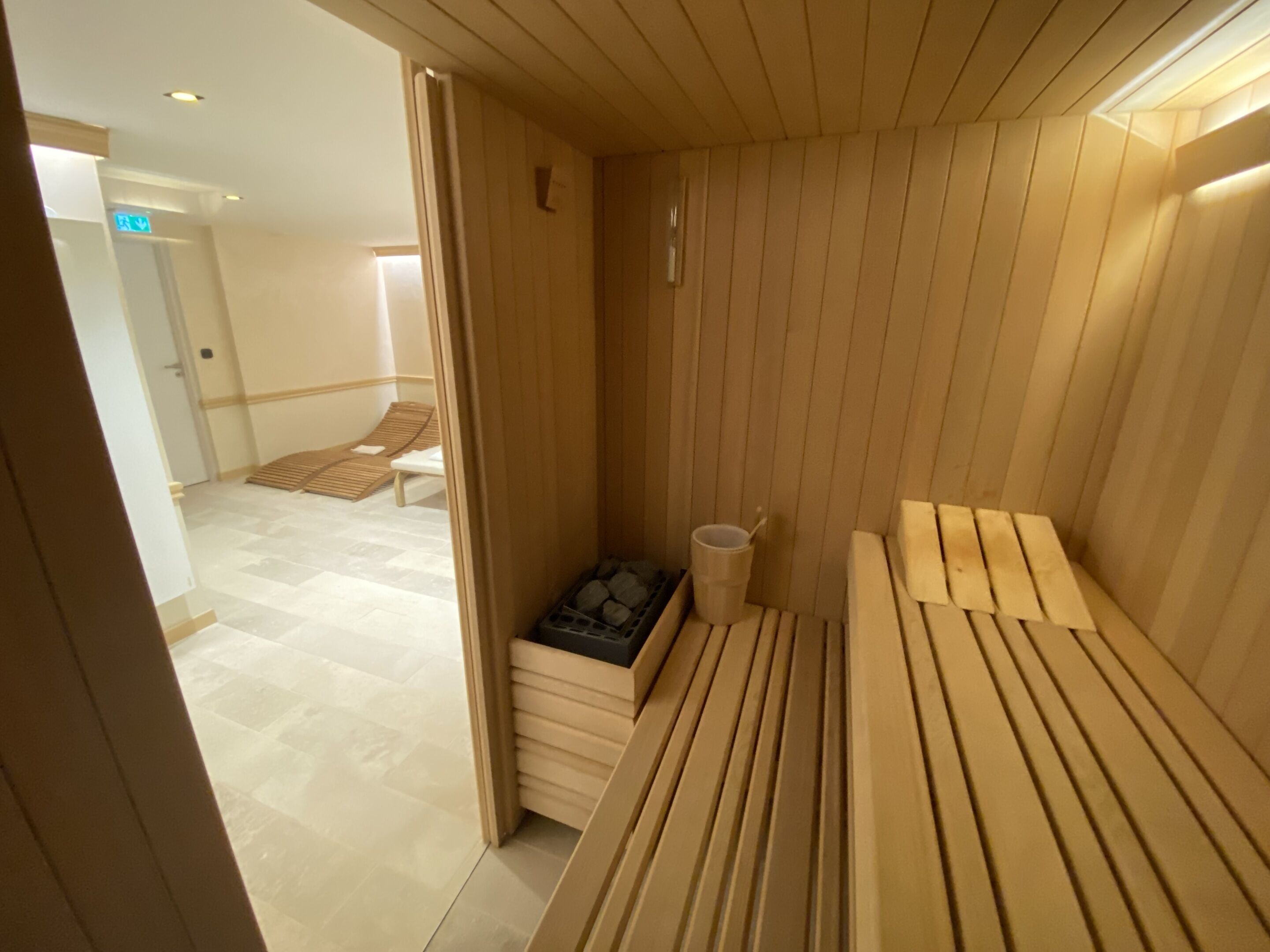 A sauna room with wooden benches and a small table with a cup.