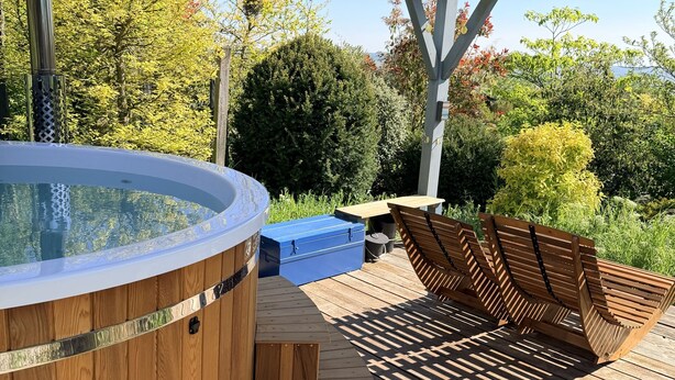 A wooden deck with a hot tub, wooden benches, and a covered area. - La Villa Mellifera (Cernay-lès-Reims)