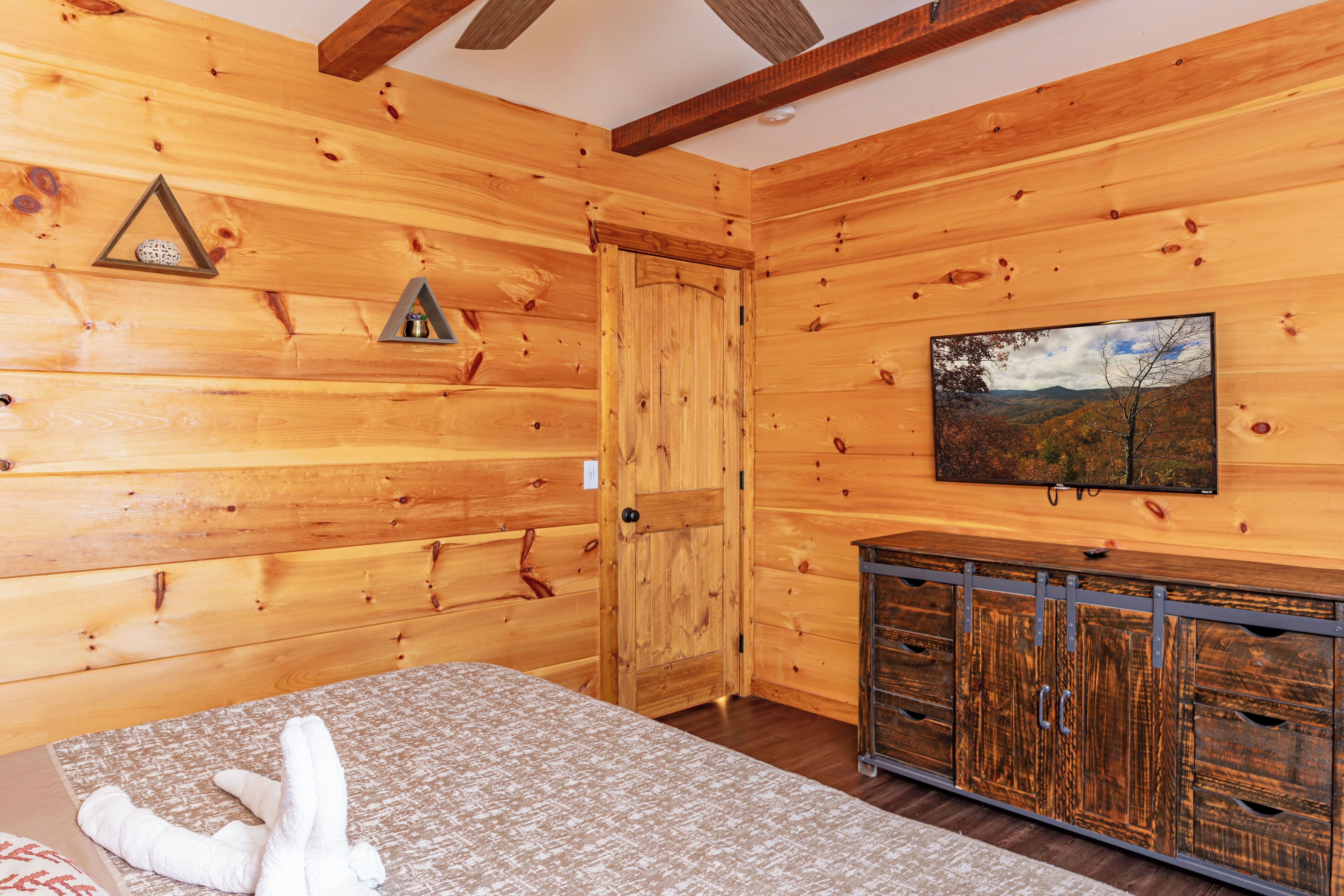 A wooden cabin room with a bed, a wooden cabinet, and a door.