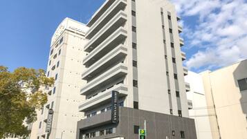 A modern hotel building with a prominent "HOTEL" sign, multiple floors, and a parking sign indicating a nearby parking area.
