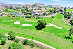Un parcours de golf avec des bunkers, un obstacle d’eau et une zone résidentielle en arrière-plan.