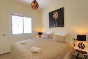 Une chambre à coucher avec un grand lit, deux lampes de chevet, une fenêtre et un tableau représentant un lion accroché au mur.