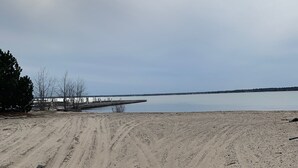 Ein sandiger Strand mit Radspuren, die zu einem Steg führen.