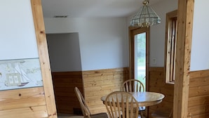 Ein Holzinnenraum mit Esstisch und Stühlen, Holzboden und einem Fenster mit Tageslicht.