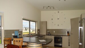 A modern kitchen with a built-in stove, sink, and a large clock on the wall. - Spacious Beach Home Away From Home (Tokerau Beach)