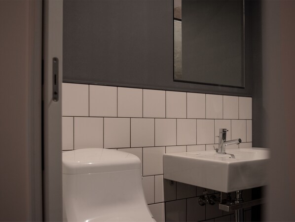 A bathroom with a toilet, sink, and mirror. - EARTHMANS Amemura (Osaka)