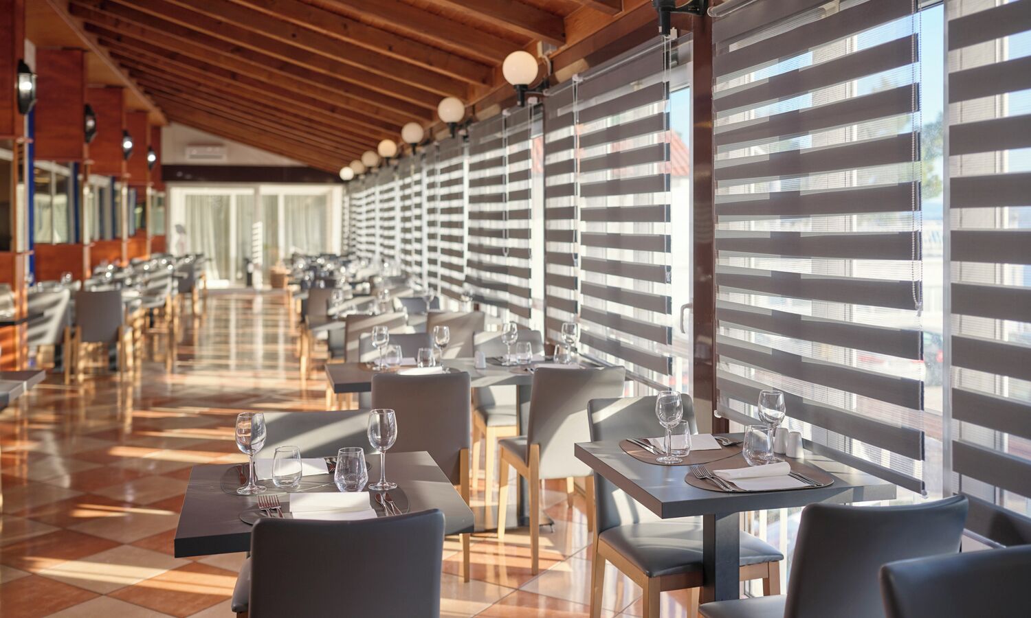 A restaurant with a long dining area, multiple tables, and chairs.