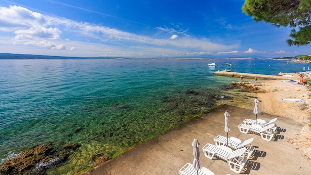 Une plage avec une eau cristalline, des chaises longues et des parasols.