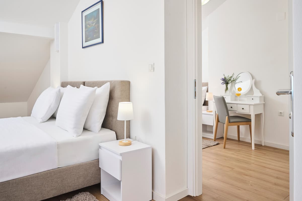 Une chambre à coucher comprenant un lit, une table de chevet, une lampe, un bureau avec une chaise et un miroir.