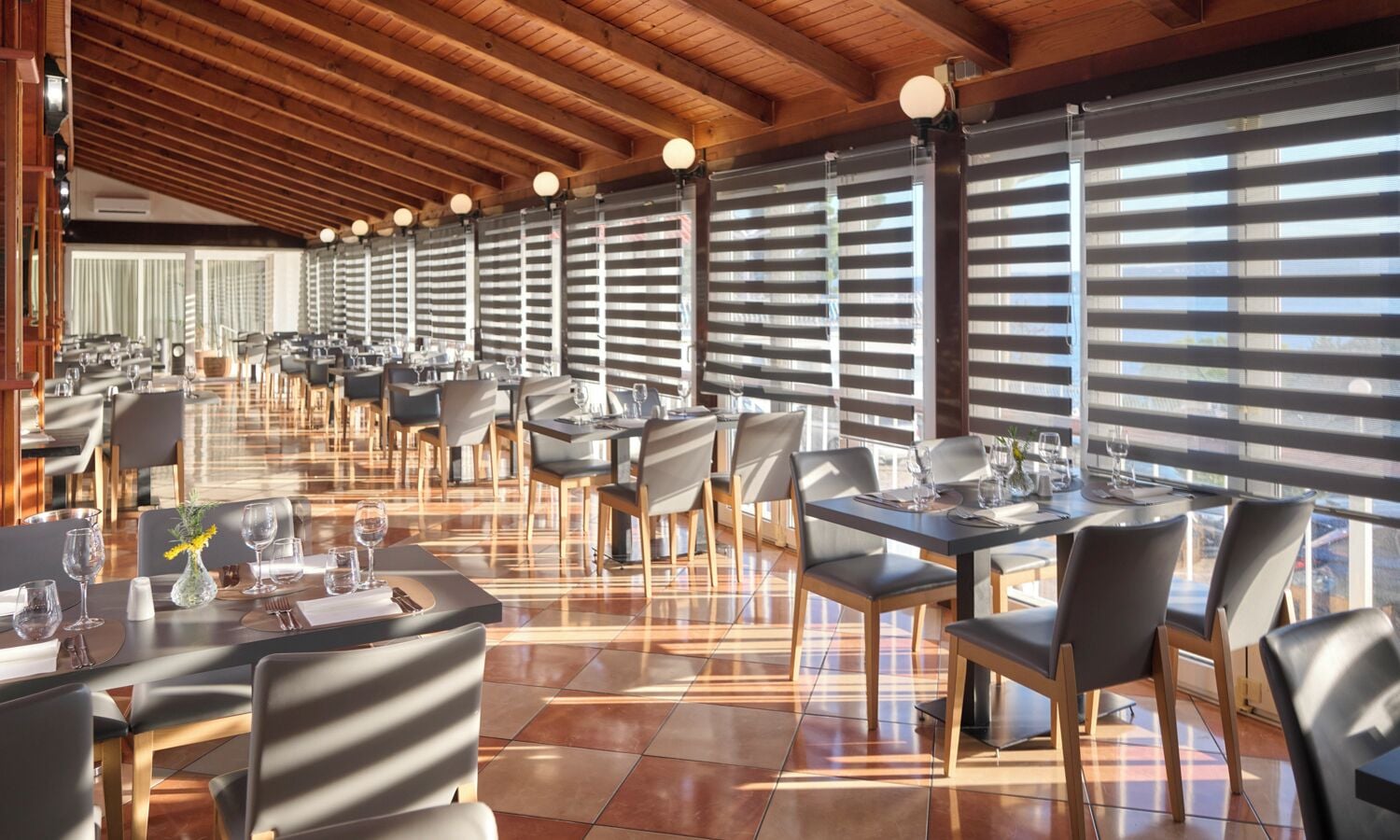 Un restaurante espacioso con techos altos y amplias ventanas, que cuenta con varias mesas y sillas para comer.