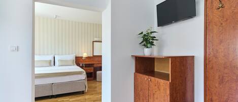 Un dormitorio moderno con cama, muebles de madera, un televisor y una planta.