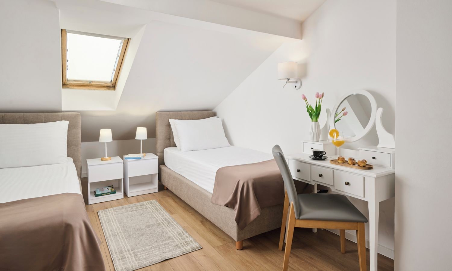 Un dormitorio con cama, mesitas de noche, escritorio, silla, espejo y ventana.