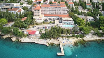 Ein Hotel am Meer mit mehreren Etagen, einem Pool und einem Strandabschnitt.