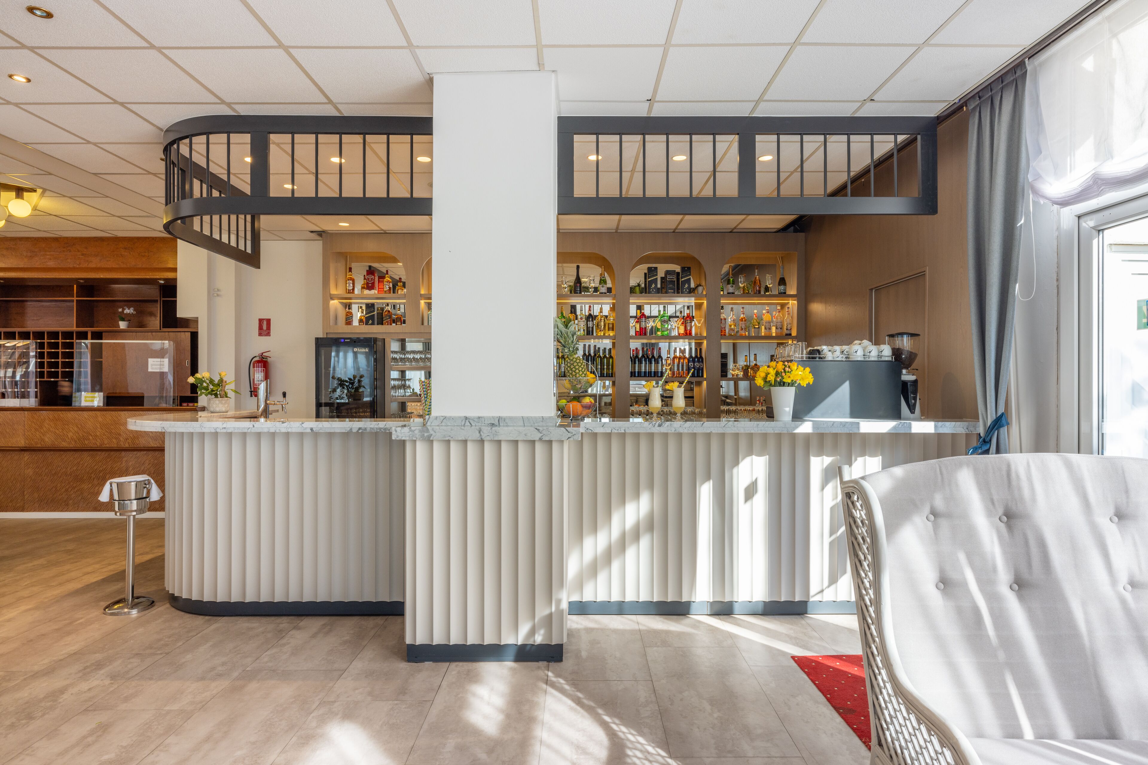 Eine moderne Hotelhalle mit Barbereich, einer Treppe und einer Sitzecke mit rotem Teppich.