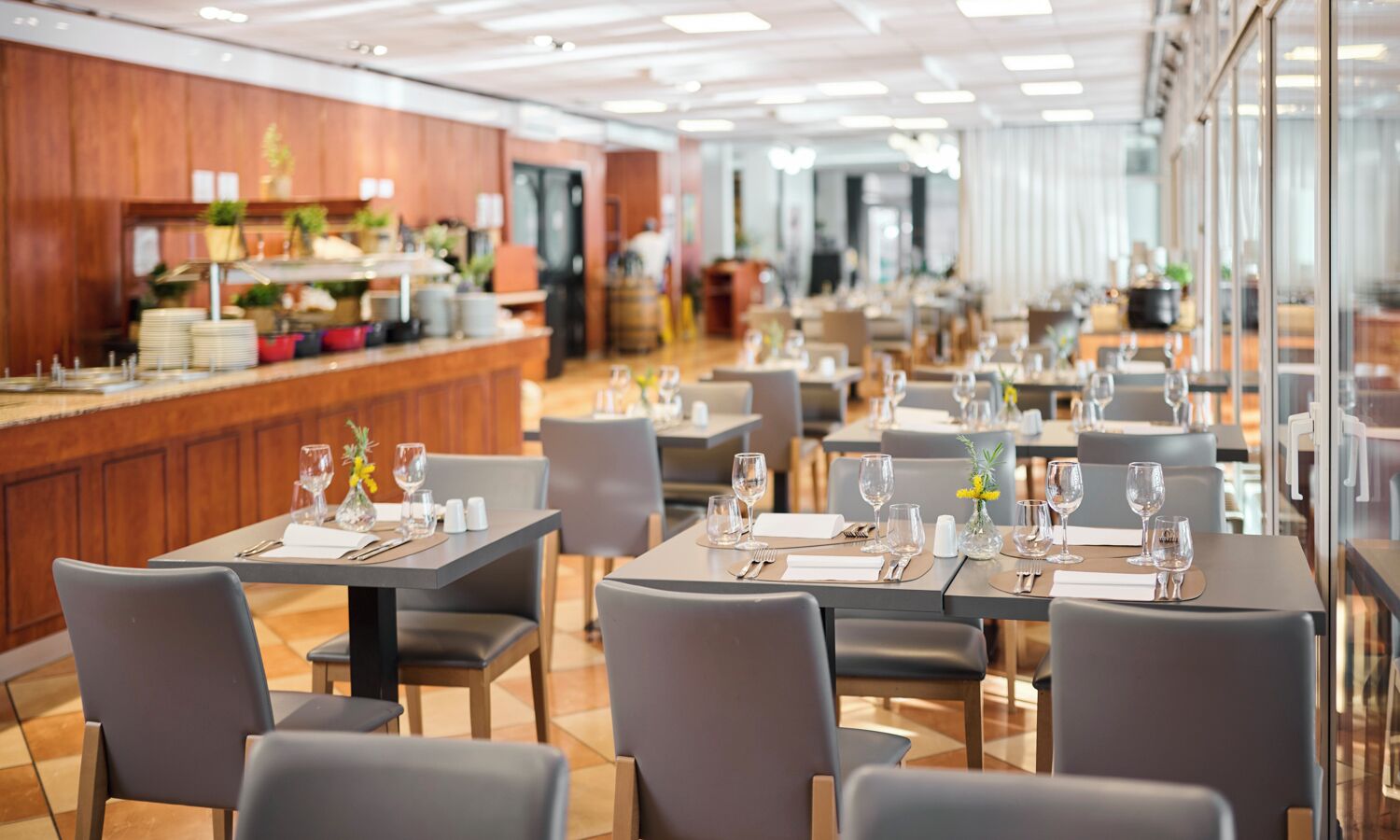 A restaurant with tables set for dining, a bar area, and a kitchen in the background.