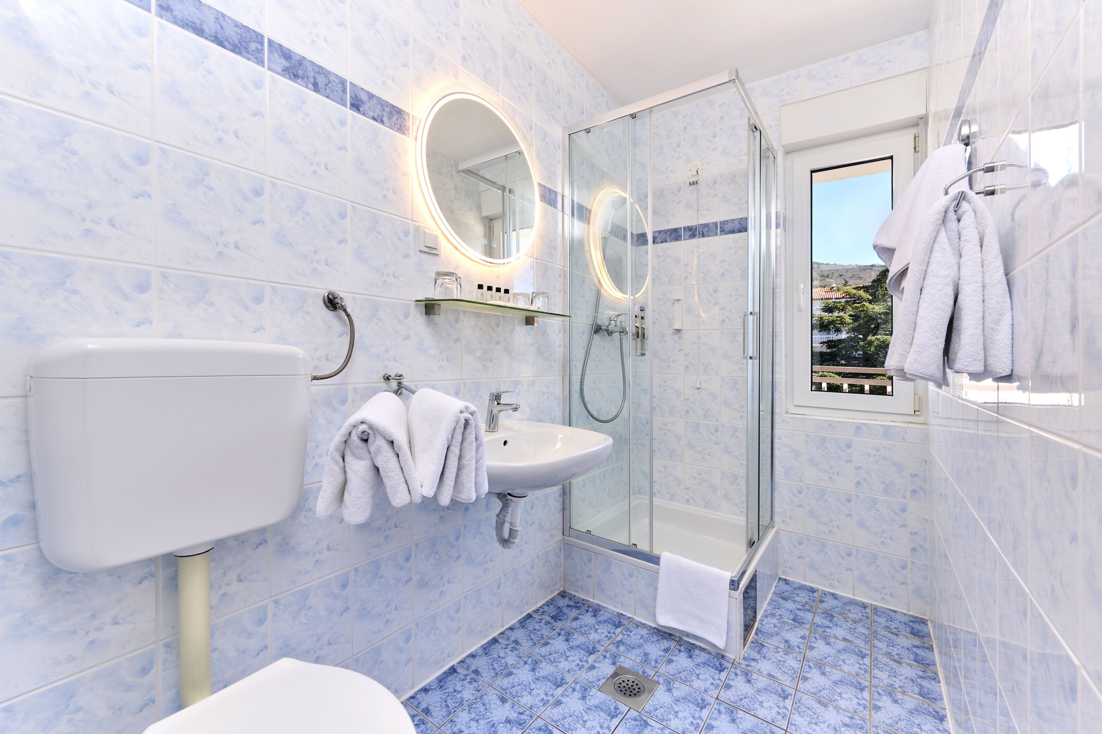 A bathroom with a glass-enclosed shower, a sink, and a toilet.