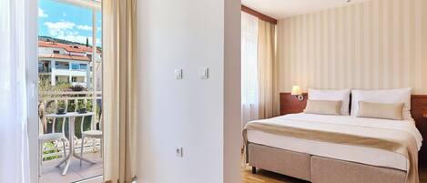 Habitación de hotel con cama, mesita de noche, una mesa con sillas y vistas al exterior.