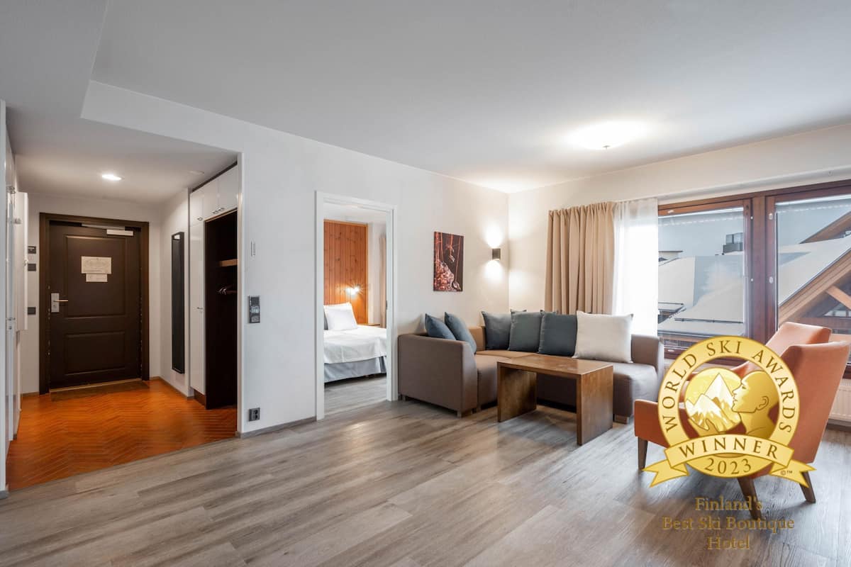 A modern hotel room with a wooden floor, a sofa, a small table, and a bed.