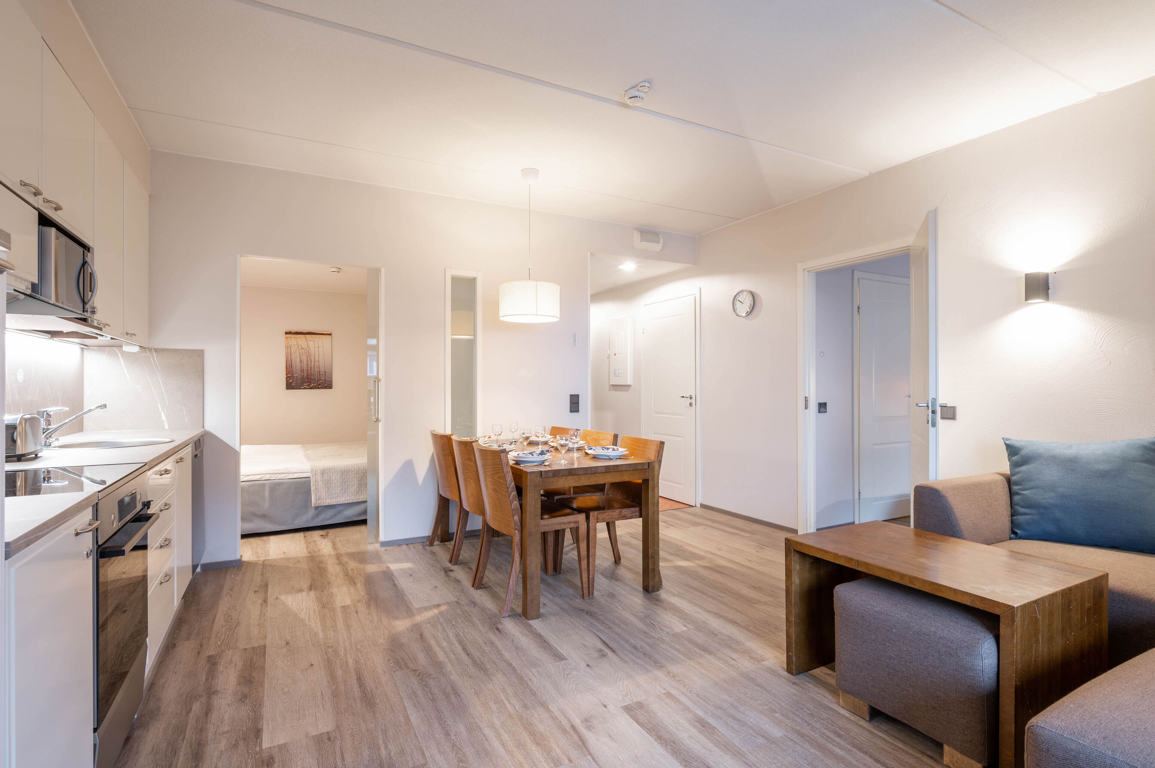 A modern kitchen with a dining area, a sofa, and a small table.